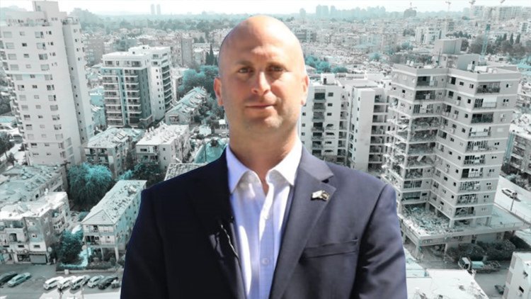 יו"ר ועדת הפנים יצחק קרויזר על רקע אתר נפילת טיל בבת ים במבצע "עם כלביא" (Bonydor, ויקימדיה, עיריית בת ים)