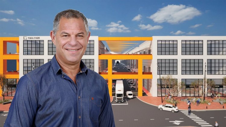 יואב שחר, מבעלי 'יוקה פארק' אחזקות, על רקע הדמיה של יוקה פארק אשקלון (הקוביה)
